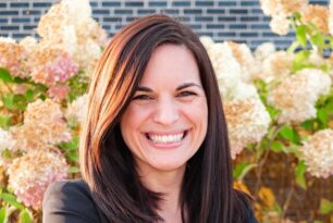 avid marketing rva founder smiling in front of flowers and brick wall